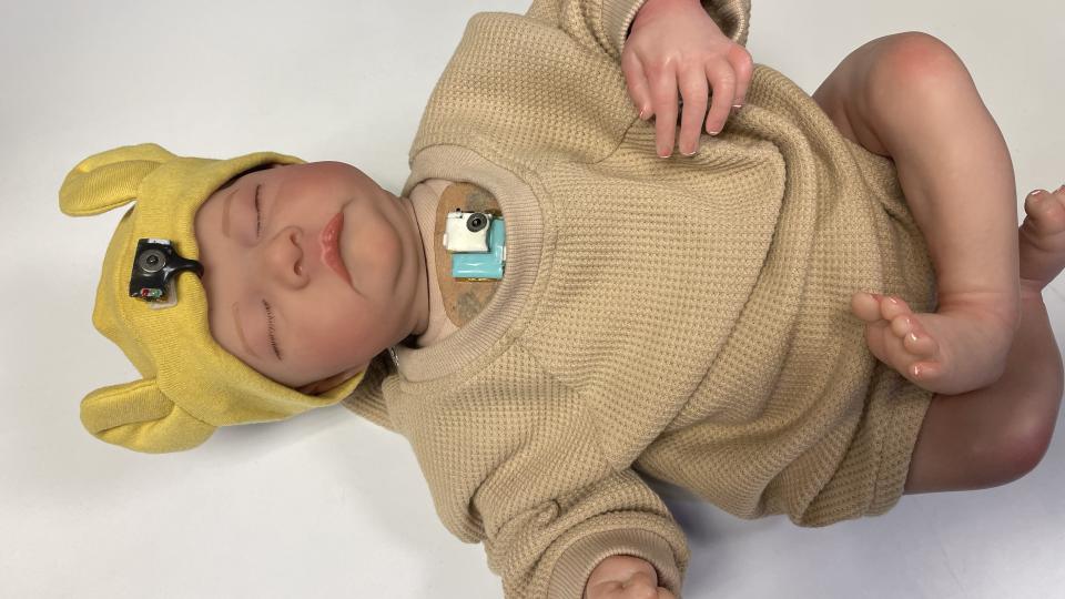 Wearable chest-mounted patch and forehead-mounted pulse oximeter shown on a mannequin baby for illustration